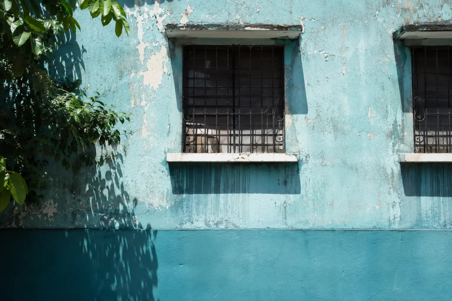Fachada de casa con pintura celeste descascarada por el sol y la lluvia
